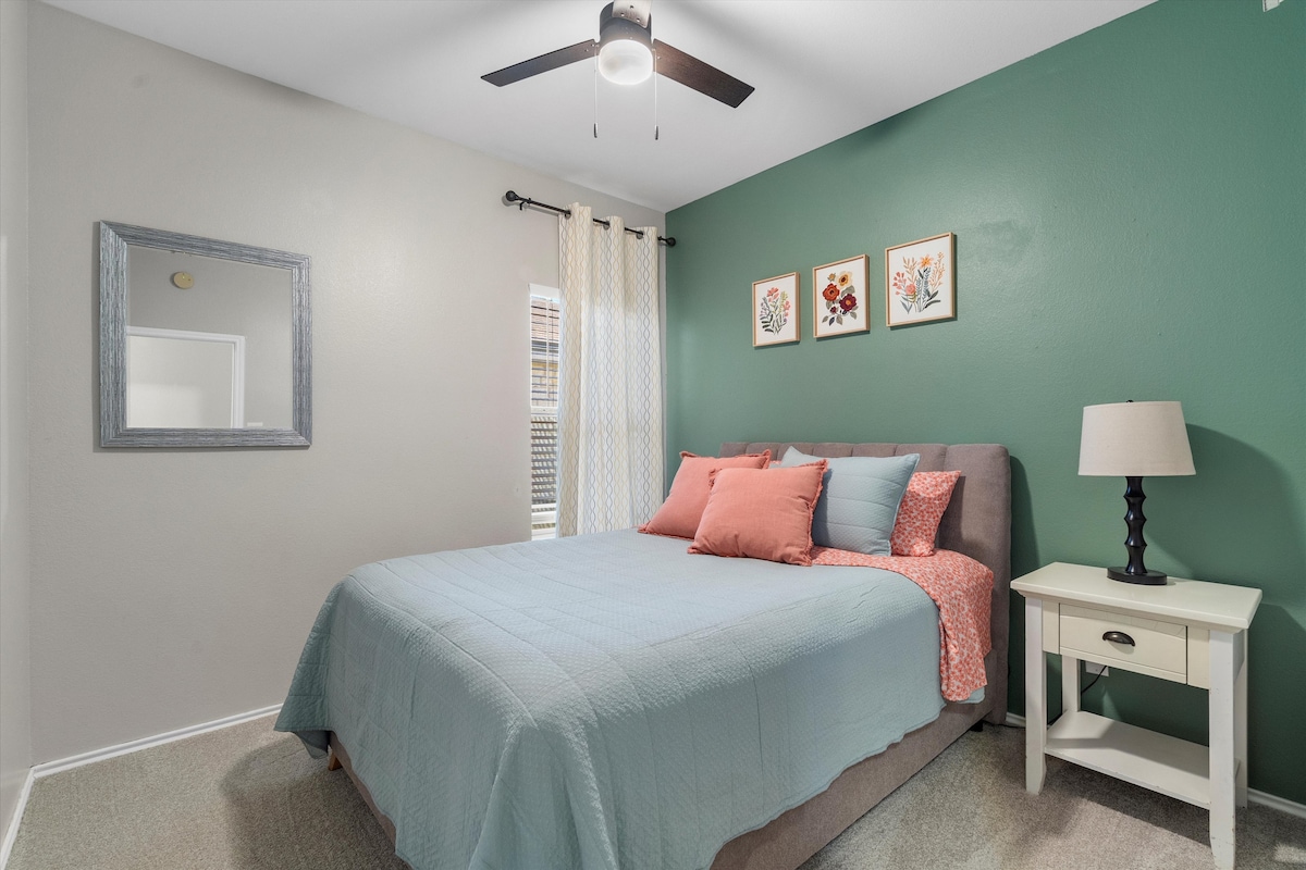 Backyard, Games & Grill guest bedroom with queen bed and floral art
